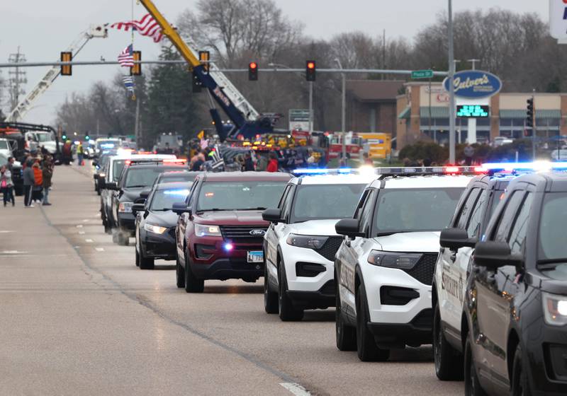 The processional honoring DeKalb County Sheriff’s Deputy Christina Musil travels through people lining the route Monday, April 1, 2024, on DeKalb Avenue in Sycamore. Musil, 35, was killed Thursday while on duty after a truck rear-ended her police vehicle in Waterman.