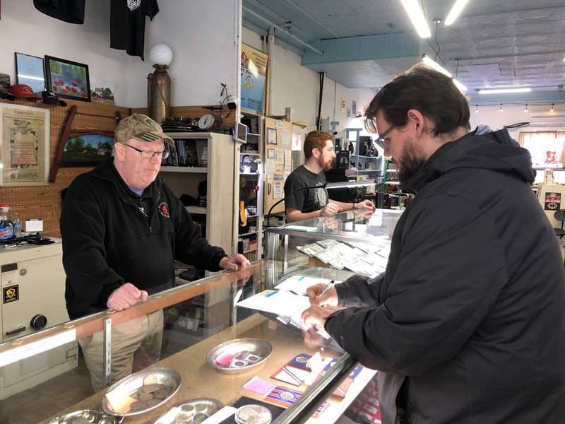 Owner Chris Drewel talks with customer Tad Becker as Becker signs Drewel's petition against the legislation threatening closure of Valley Coin and Pawn in Spring Valley on Wednesday, Dec. 28, 2022.