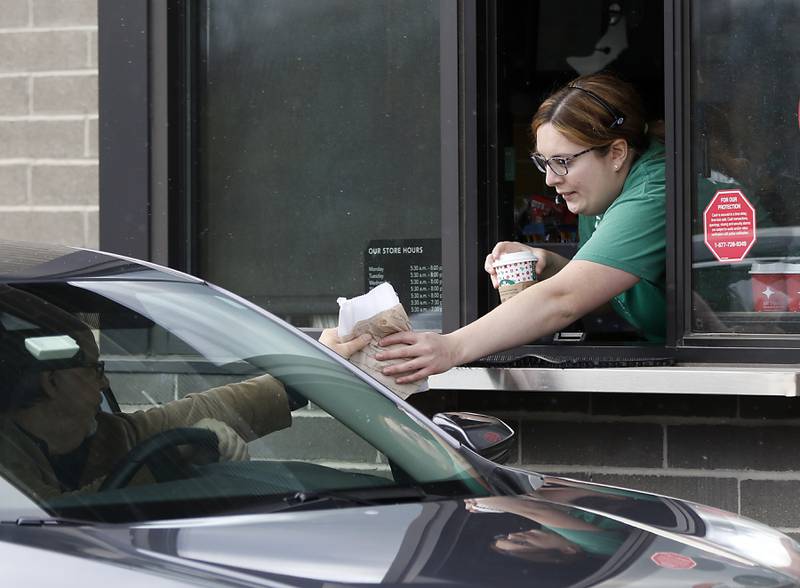 A Starbucks worker hands a customer their order Thursday, Nov. 17, 2022, at the Cary Starbucks location on Starbucks' Red Cup Day. Workers at Starbucks in Cary joined other workers across the country seeking to convince the company to better negotiate with its unionized locations.