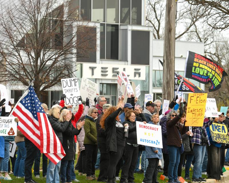 Community members line Ogden Ave. holding signs and flags near the Tesla dealership on Saturday April 5, 2025, in Lisle during the Hands Off Demonstration.