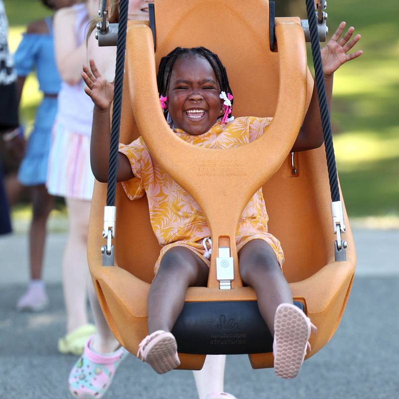 Delilah McClain, 5, from DeKalb, rides the zipline Friday, June 14, 2024, at the new playground at Hopkins Park during a Dedication Celebration event for the grand opening of the new playground and racquet courts.