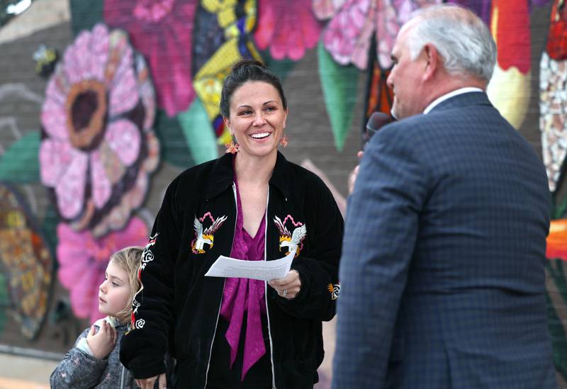 Mural artist Danielle Casali is introduced by Brad Hoey with the The DeKalb County Convention and Visitors Bureau Thursday, Oct. 19, 2023, during the unveiling and ribbon cutting of the new City Hall mural she created. The mural is on the on the south wall of City Hall and was completed with the help of many volunteers who wanted to be a part of the project.