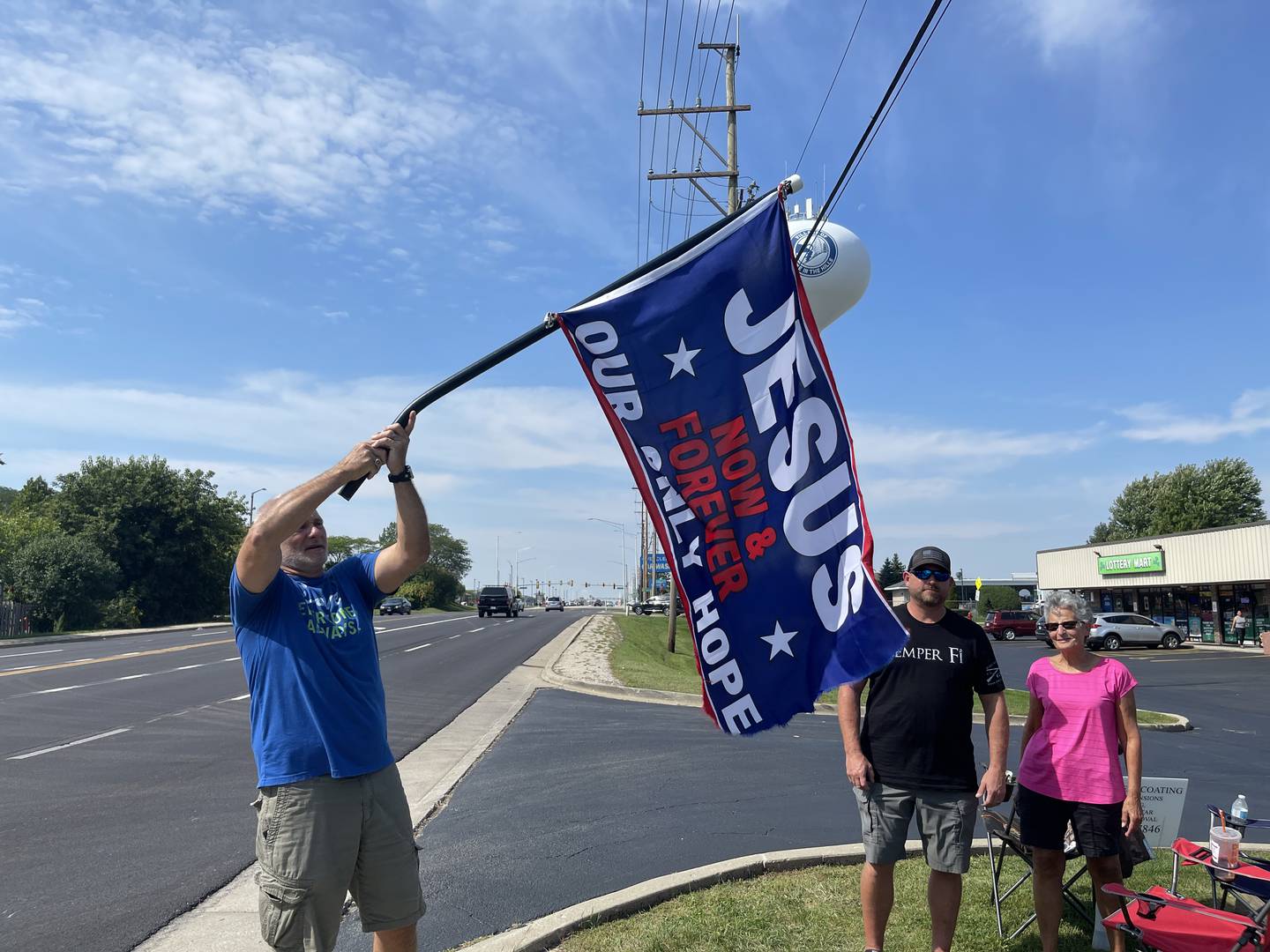 James Gustafson waves a flag that says "Jesus Our Only Hope" outside of UpRising Bakery in Lake in the Hills on Saturday, Sept. 17, 2022.