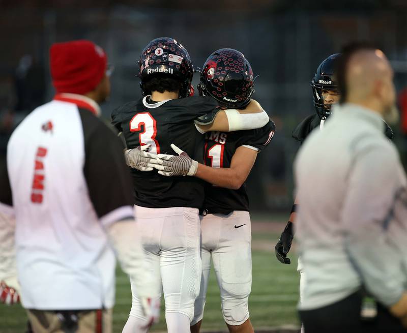 Glenbard East's Gianbiagio Brusca (3) and Aaron Dotson (11) embrace after their loss to Normal during the IHSA Class 7A quarterfinals Saturday November 11, 2023 in Lombard.