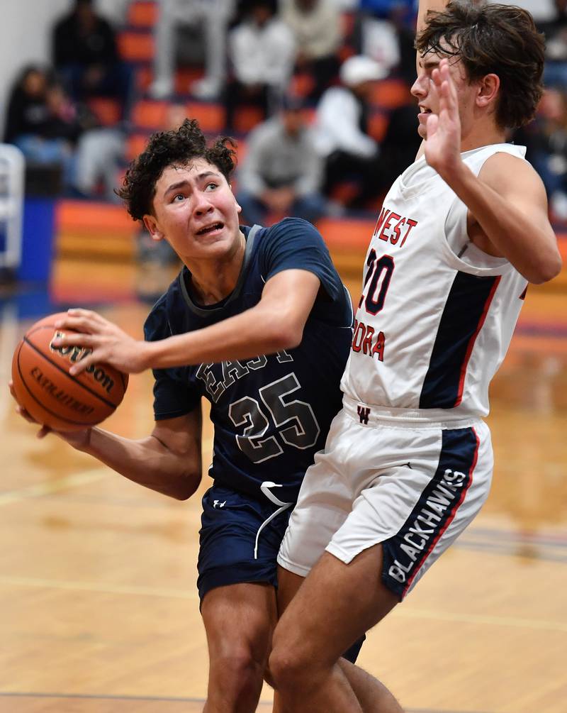 Oswego East's Damien Lewandowski (25) goes to the basket as West AuroraÕs Billy Samp defends during a Hoops for Healing tournament game on Nov. 20, 2023 at Naperville North High School in Naperville.