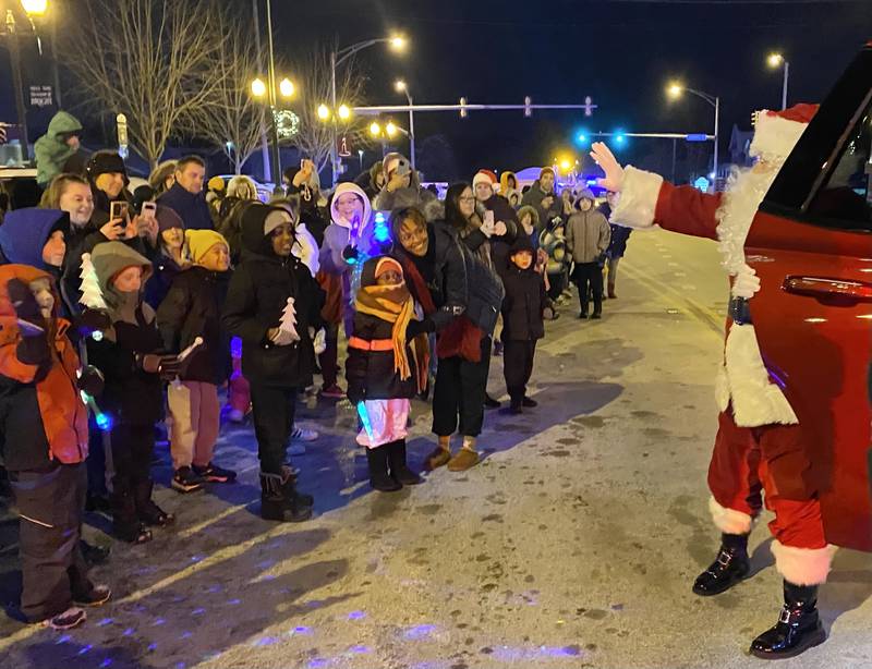 Santa Claus waves as he greets waiting on Friday, Dec. 5, 2025, ready to walk with him downtown at the Sycamore Chamber of Commerce's annual Walk with Santa.