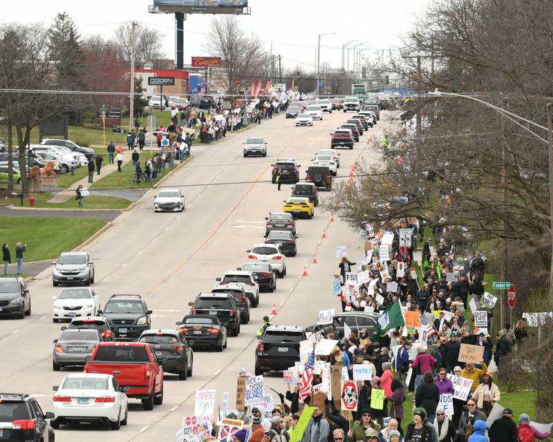 Community members line Ogden Ave. holding signs and flags near the Tesla dealership on Saturday April 5, 2025, in Lisle during the Hands Off Demonstration.