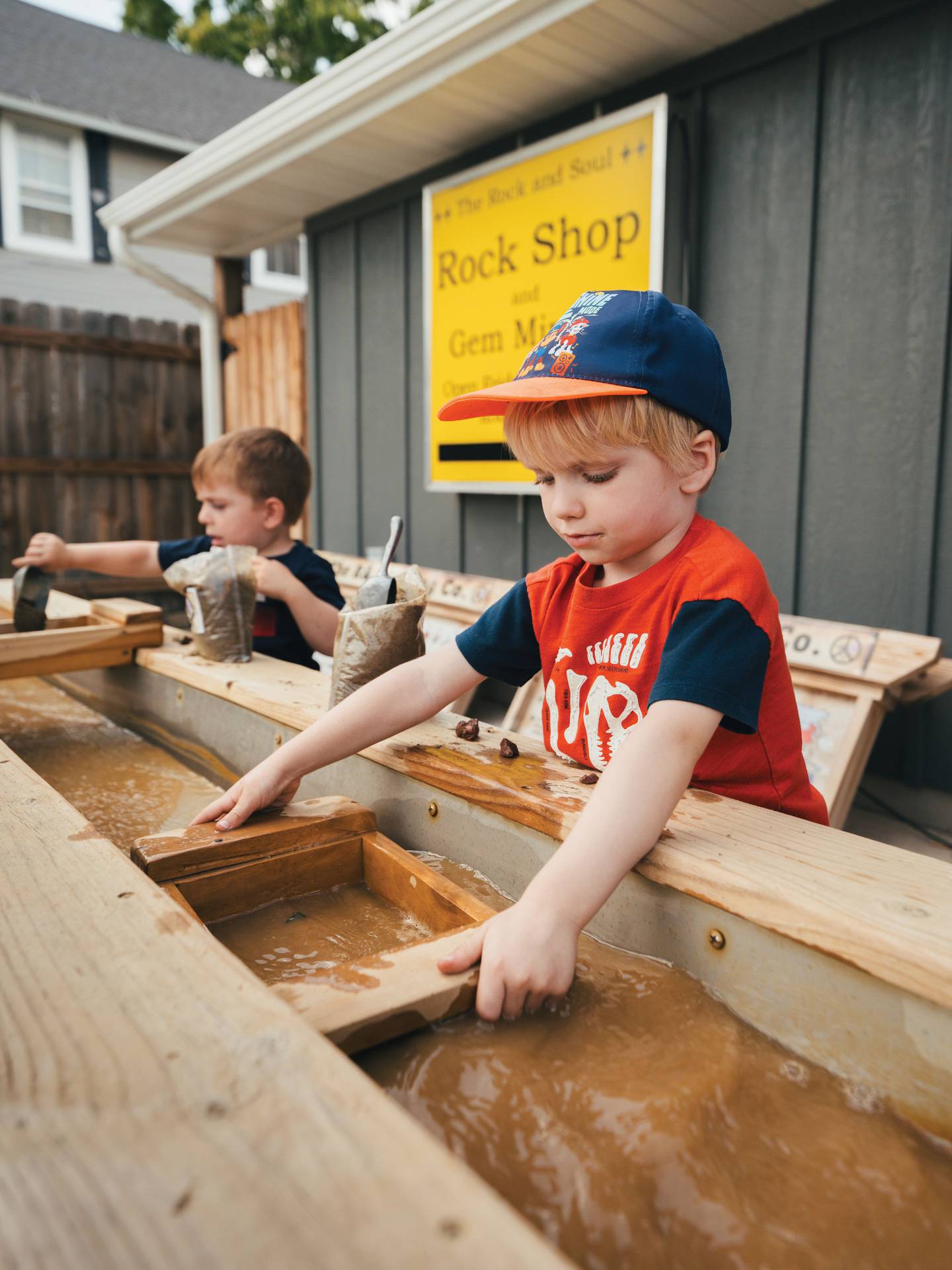 Children sift pans of dirt in the outdoor sluice box at The Rock and Soul in Utica. Families can buy a sluicing bag, which contains concealed rocks, gemstones, fossils and more. Children can then go outside to rinse away the dirt to discover their treasures.