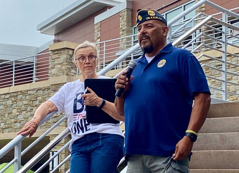 Cindy Hupke (left), member of the American Legion Post No. 66 Auxiliary and head organizer, looks on as Legion Post Cmdr Manuel Olalde (right), gives opening remarks at the inaugural Be the One Walk to spread awareness about veteran suicide rates. The 2.2-mile trek to mark the roughly 22 veterans who die by suicide daily set out from Northwestern Medicine Health and Wellness Center, 626 Bethany Road, DeKalb, and drew a large crowd Sunday, Sept. 22, 2024.
