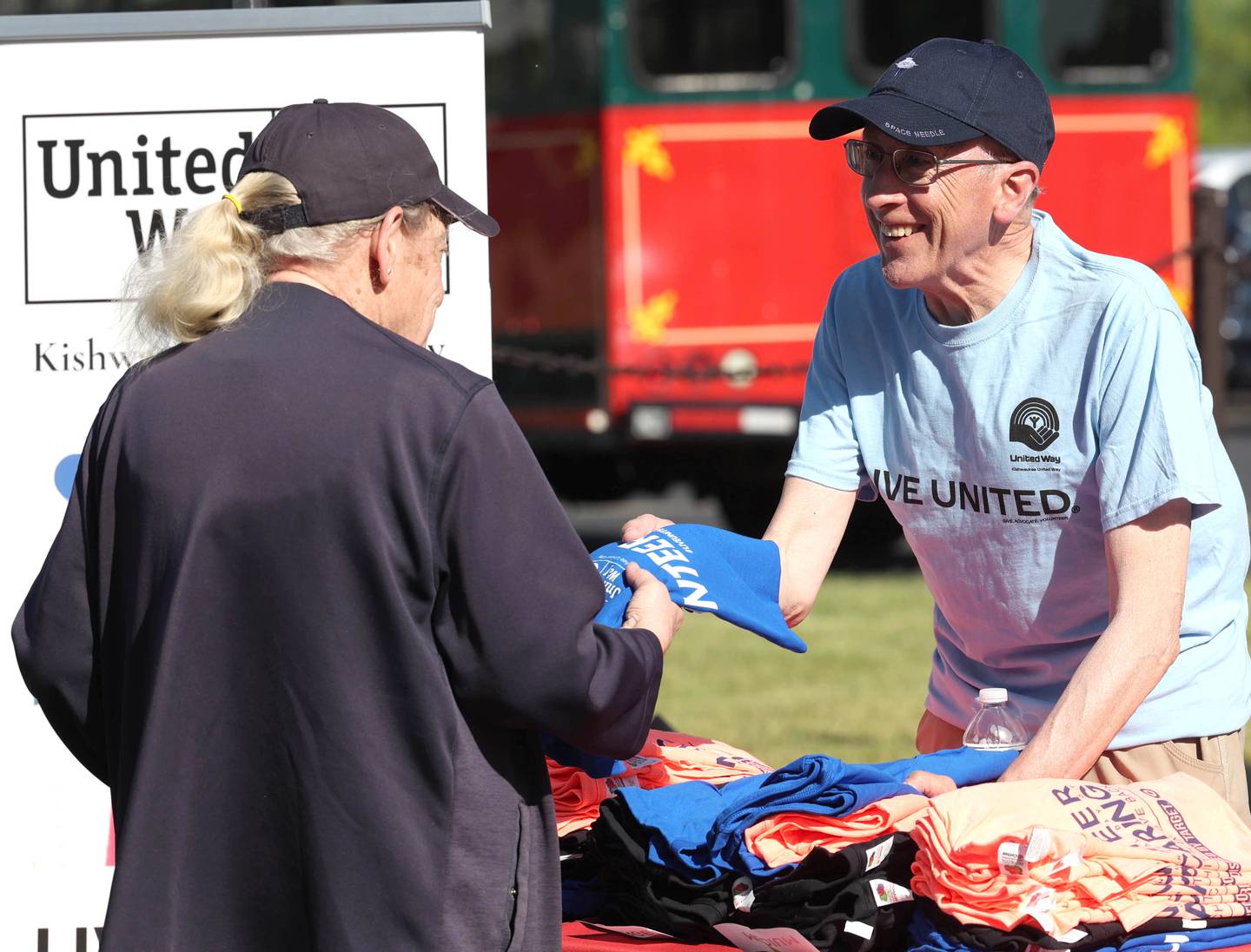 Paul Callighan, a member of the Kishwaukee United Way Board of Directors, hands T-shirts out to volunteers Thursday, June 13, 2024, during the kick-off of Kishwaukee United Way's annual Day of Caring event.