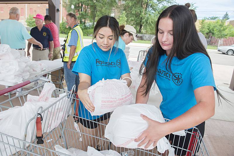 Sauk Valley College Rotaract members Jennifer Brito (left) and Meg Frank place meals for delivery into a cart on Monday.