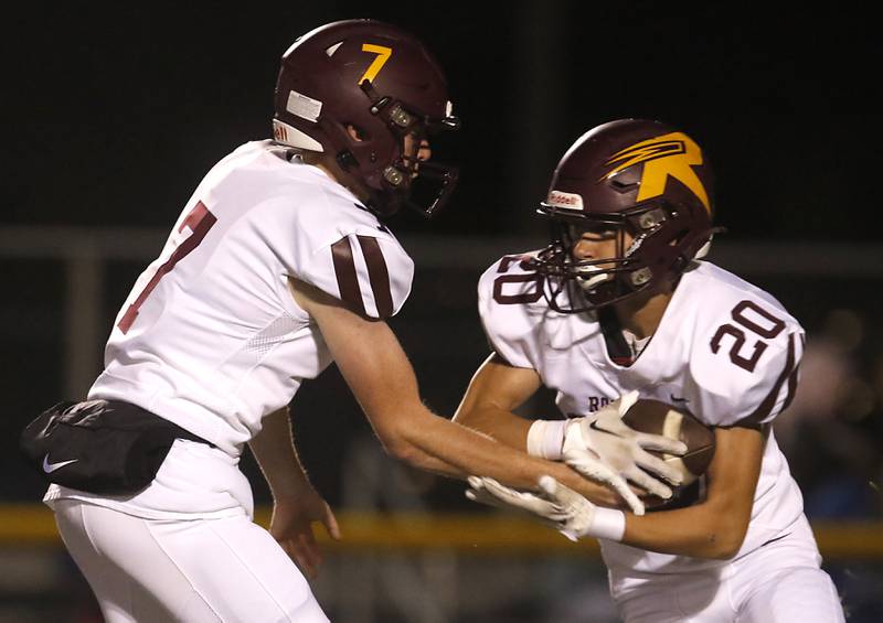 Richmond-Burton's JT Groh hands the ball off to Luke Johnson during a Kishwaukee River Conference football game against Johnsburg on Friday, Oct.6, 2023, at Johnsburg High School.