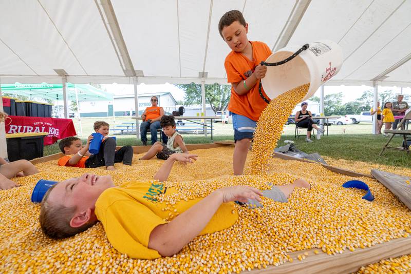 Parker Hettel (front) laughs as his friend Aaron Fulkerson attempts to bury him in the corn play area at the LaSalle County 4H Fair on July 10, 2025 in Ottawa.