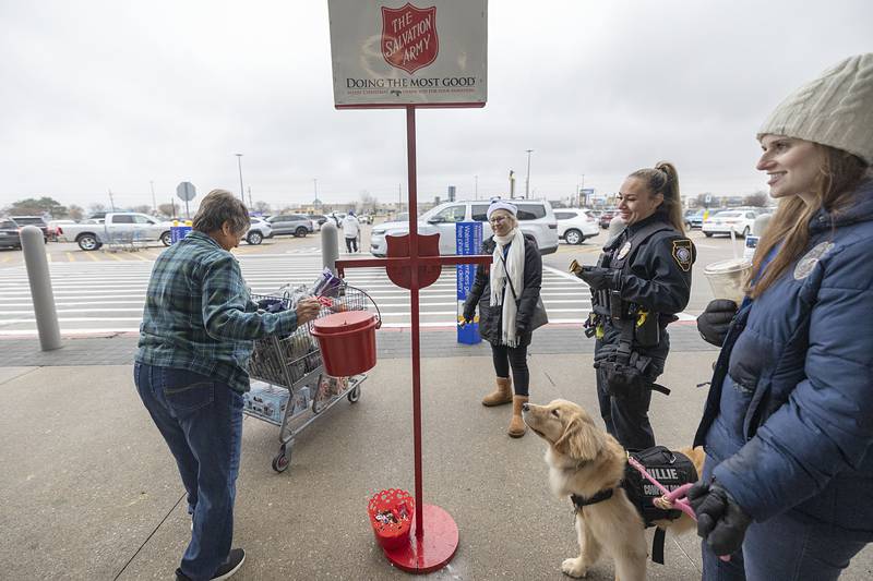 A donor drops in some cash as Sterling police’s Lisa Tate (middle left), officer Sierra Jenkins, Mary Toth and Millie thank them Thursday, Nov. 20, 2025, outside of the Sterling Walmart. The police and fire departments went head to head in donation collections to help benefit the Salvation Army.