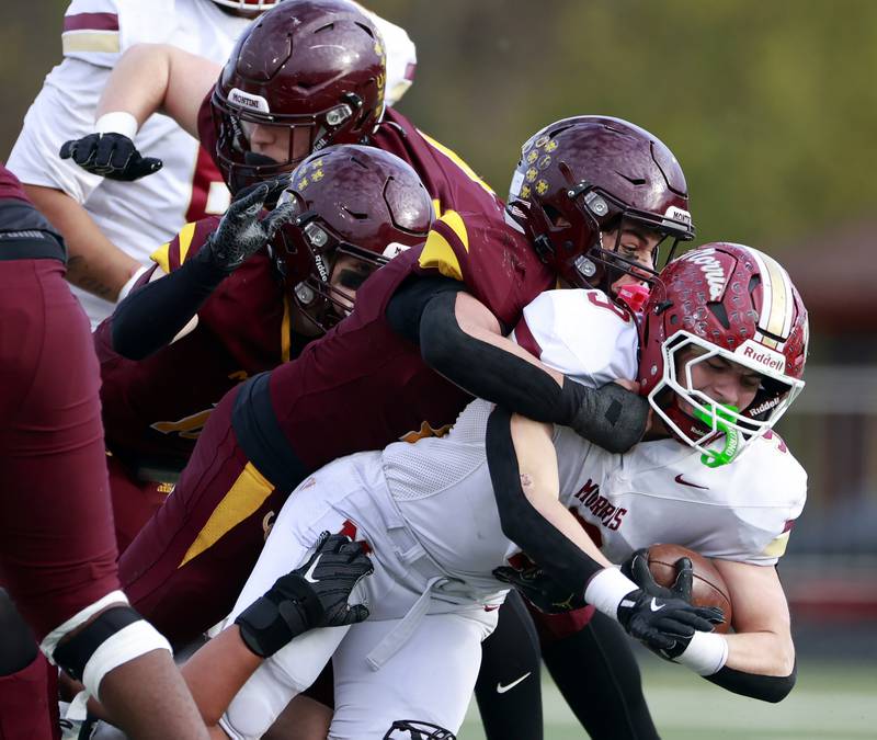 Morris' Caeden Curran (9) is brought down by a host of Montini players during the IHSA Class 4A semifinals football playoff game Saturday, Nov. 22, 2025 in Lombard.