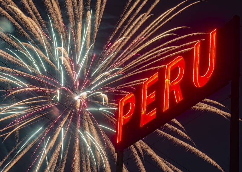 Multiple fireworks burst over the neon Peru sign on Water Street during the fireworks on Monday, July 3, 2023.