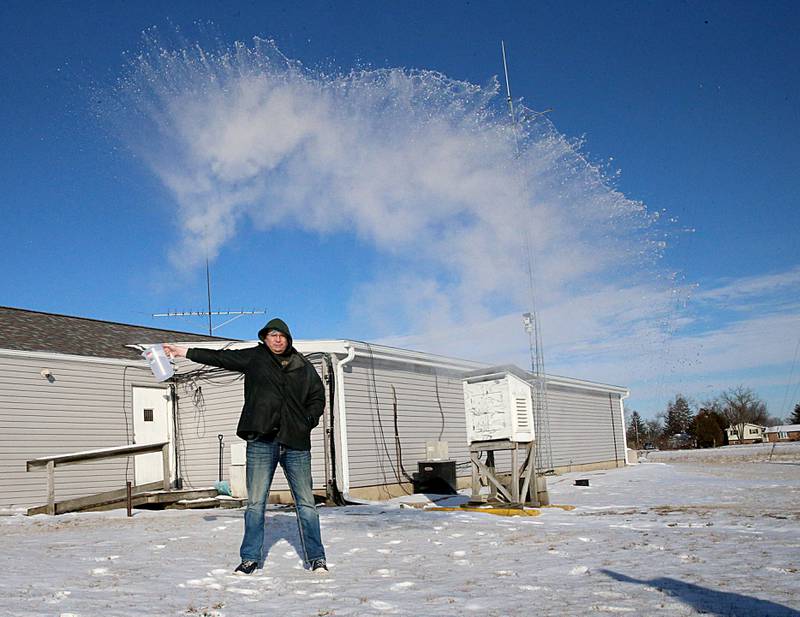 Brad Spelich, morning host on WAJK, throws a pitcher of hot water in the air in the frigid temperatures on Tuesday, Jan. 31, 2023 at Starved Rock Media in Oglesby. Throwing boiling water in the air when the temperatures are very cold can create a stunning effect as it evaporates and condenses into steam.