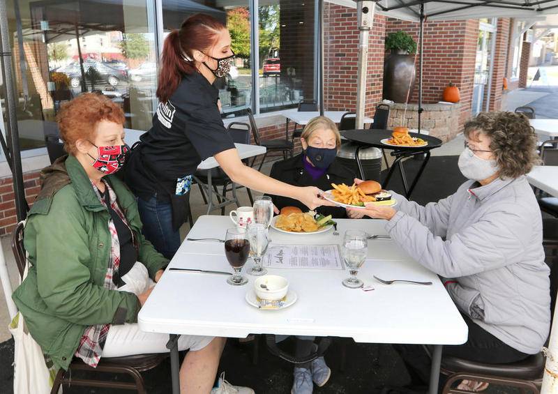 Lincoln Inn at Faranda's waitress Tiffane Barreto brings out lunch for Jeanette Biava, (left) of DeKalb, Beverley Lane, from Sycamore, and Carolynn Werline, (right) also of Sycamore, who were dining outside under a heated tent Friday at the restaurant in DeKalb. The Illinois Department of Public Health announced earlier this week that Region 1, which includes DeKalb and Sycamore, must once again close indoor dining at restaurants and limit gatherings to 25 people or less starting Saturday.