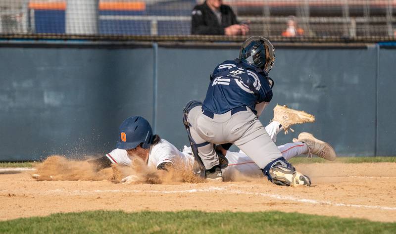 Oswego’s Ethan Valles (5) makes a head first slide to beat the throw to home against Plainfield South during a baseball game at Oswego High School on Monday, April 11, 2022.