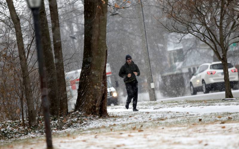 A jogger runs along Prairie Street in St. Charles at the start of a snow storm on Thursday, Dec. 22, 2022.