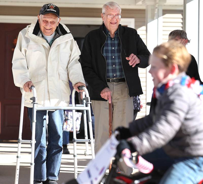 US Navy veteran Richard Korleski, (left) 93, and Ken Cooper, 96, a US Army veteran, smile as they watch members of the Kunkel family pass by in a small parade on Veterans Day,  Friday, Nov. 11, 2022, at the Grand Victorian assisted living facility in Sycamore. Sycamore resident Joann Kunkel read a story in the current Midweek that contained a quote from one of the veterans at the facility that lamented the lack of a parade. So she and her grandkids decided to have one for them.