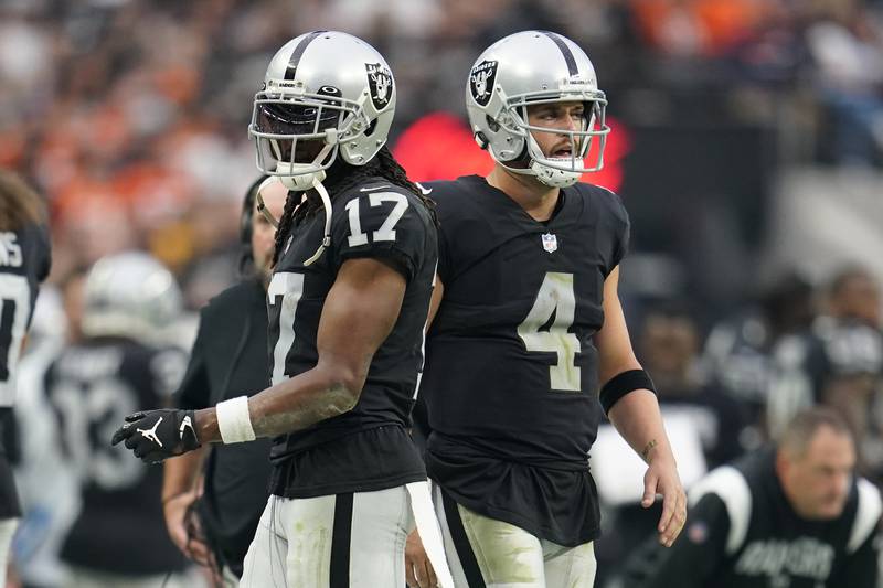 Las Vegas Raiders wide receiver Davante Adams (17), left, and Las Vegas Raiders quarterback Derek Carr (4), right, look on from the sidelines during the second half of an NFL football game. (AP Photo/Abbie Parr)