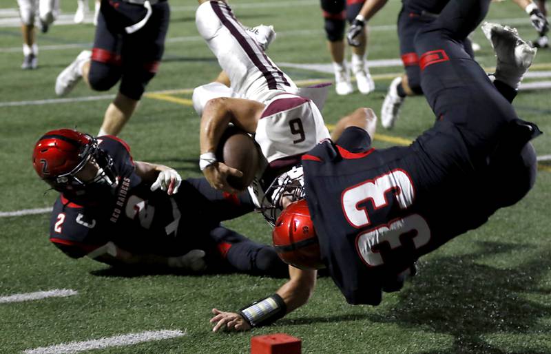 Prairie Ridge's Luke Vanderwiel flies to the ground as he tries to get into the engine after being hit by Huntley's Colin Masten (left) and Charles Condon III (right) during a Fox Valley Conference football game on Friday, Sept. 20, 2024, at Huntley High School.