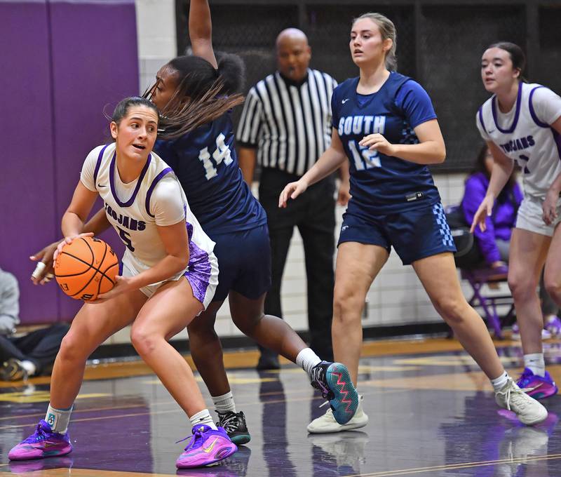 Downers Grove North’s Campbell Thulin looks to pass after coming down with a rebound in front of Downers Grove South’s Ionna Griffin during a game on December 20, 2025 at Downers Grove North High School in Downers Grove.