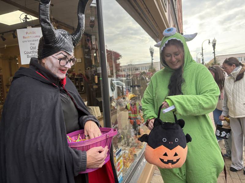 Cindy Huffman passes out candy at Down2Earth while Taylor Bukowski, right, looks on during Halloween on the Square in Woodstock Oct. 31, 2025.