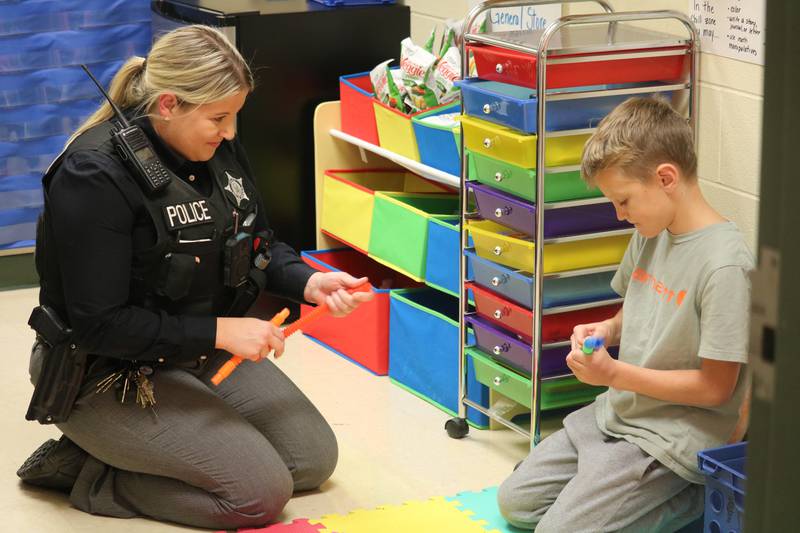 DeKalb Police Officer Allison Remnes (left)  and Trey Lawrence (right) are seen Oct. 20, 2022 in Remnes' office at Gwendolyn Brooks  Elementary School in DeKalb.