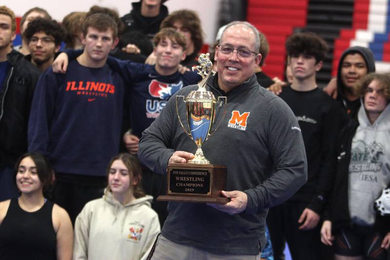 McHenry’s Head Coach Dan Rohman accepts the Fox Valley Conference championship trophy after the Warriors clinched an outright title with a win over Dundee-Crown in varsity wrestling at Carpentersville Thursday night.