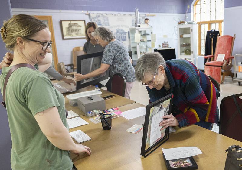 Phidian member Claudia Nelson (right) checks in art pieces submitted by Liz Coss Monday, April 13, 2026, for the annual Phidian Art Club’s 2026 show. Work can still be submitted Tuesday from 2-6pm at the Loveland House in Dixon. Awards will be handed out Thursday with doors opening at 6pm for public viewing.