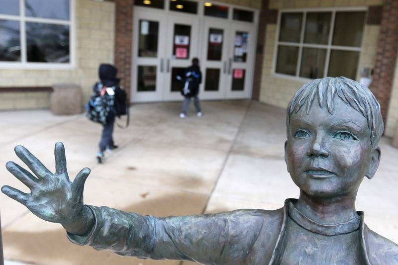 Leggee Elementary School students head into school, past the "Joy of Learning" sculpture at the main entrance, on Monday, Jan. 25, 2021, in Huntley.