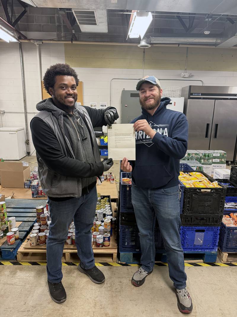 Rooted for Good employees Kyle Moore (left) and Joseph Ruehl (right) display their Promise Grant award letter for the purchase of highly requested hygiene products.