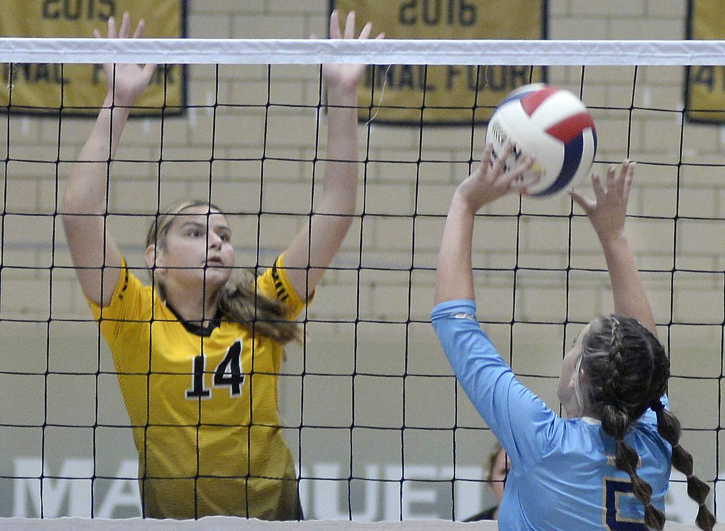 Marquette’s Kealey Rick works to get the ball over as Reed-Custer’s Madison Keenan sets to block during the second set Monday at Marquette High School.