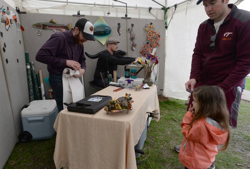 Olivia and Jeff Mariner of Elmhurst make a purchase with the help of (left) Austin Dickel and Sam Seigal of Iowa during the Elmhurst Art Festival Saturday April 30, 2022.