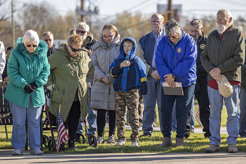 Visitors to Saturday’s Veterans Day ceremony stand for the final prayer November 11, 2023.