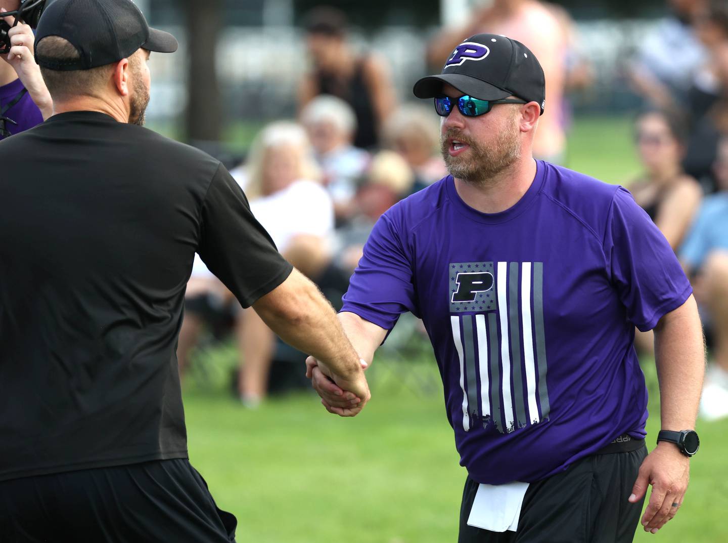 New Plano head football coach Kyle Tutt (right) shakes hand with Kaneland head coach Mike Thorgesen after their matchup Tuesday, July 16, 2024, in the Kaneland 7-on-7 at the school in Maple Park.