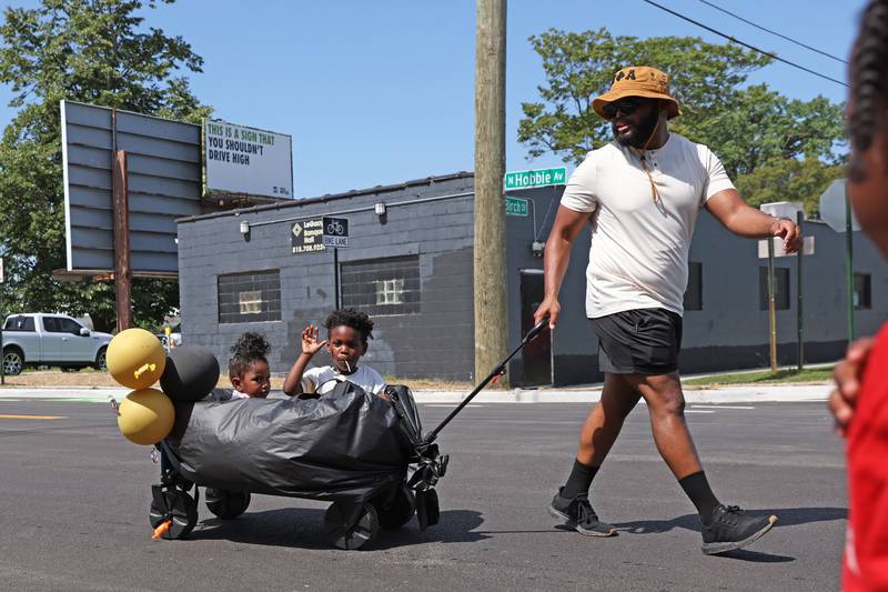 Vince Clark and his children Nevaeh, 3, and Christian, 5, pass out candy along the parade route during the annual Kankakee Juneteenth Parade on Saturday, June 21, 2025.