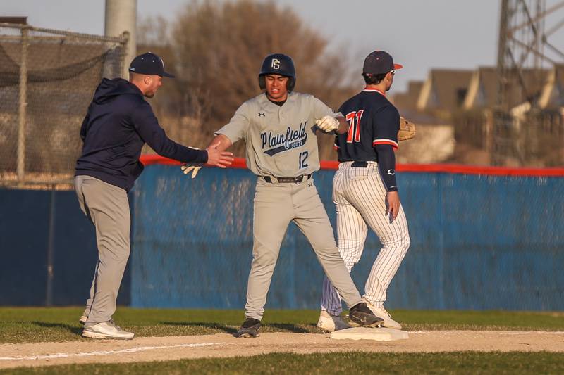 Plainfield South's Mateo Osorio (12) is greeted at third after hitting a triple during baseball game between Plainfield South at Oswego on Monday, April 14, 2025 in Oswego.