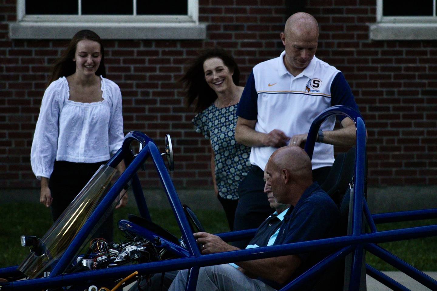 Sterling Public Schools Superintendent Tad Everett settles in behind the wheel of a Switch electric vehicle on Wednesday evening at the high school. Director of Finance Timothy Schwingle is the passenger. The car was assembled by physics students as part of an instructional kit. From left, is one of the students who worked on the project, Paige Geil, board member Julie Zuidema, and Principal Jason Austin. During the demonstration, members of the board and school administration took turns driving it across the nearby parking lot.