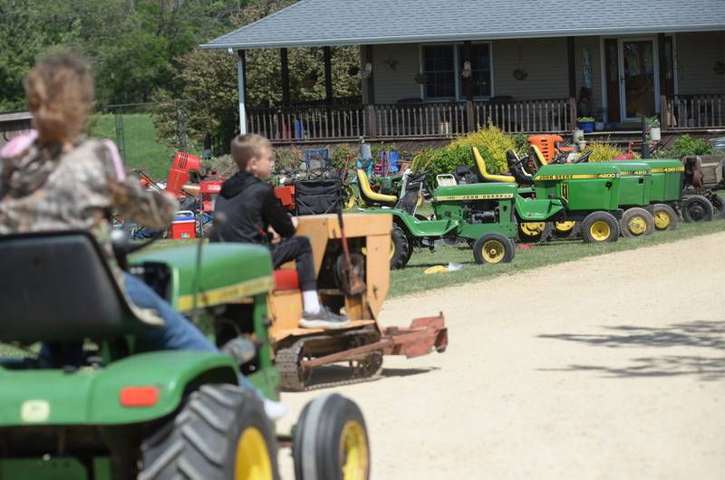 Cody and Katie Kitson, 10 and 12, drive their lawn tractors past a row of John Deere tractors at the 16th Annual AJ’s Garden Tractor Jamboree on Saturday, May 17, 2025 at 1675 S. Columbian Rd., Oregon. Cody was driving a 1965 Lennox Kiddie Trac that was designed with a mower deck and snowblower.