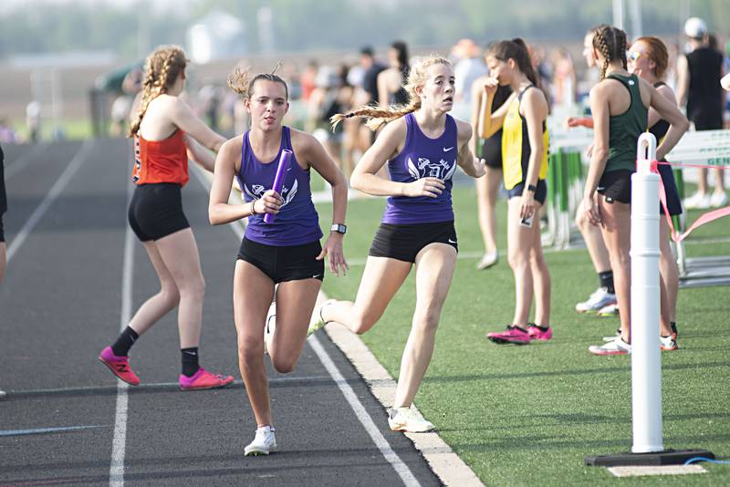 Dixon's Keeley Mick takes the baton from Emma Smith in the third leg of the 4x800 at the 2A track sectionals in Geneseo on Wednesday, May 11, 2022. Dixon won the event.