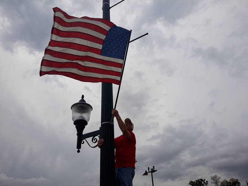 Hardscrabble Lions Club member Bud Wahl installs the American flag on a light post Thursday, May 26, 2022, in downtown Streator. Members of the Hardscrabble Lions put up flags on several light posts along Main Street.