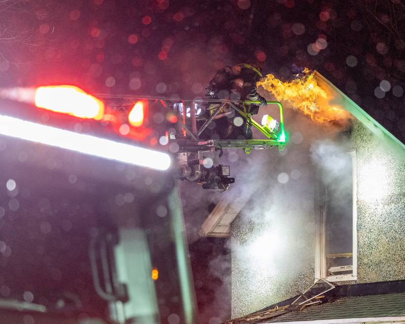 Firefighters standing outside front door of a '2nd Alarm' house fire point towards flame on Saturday, January 10, 2026, at 217 West Delvin Street in Spring Valley.