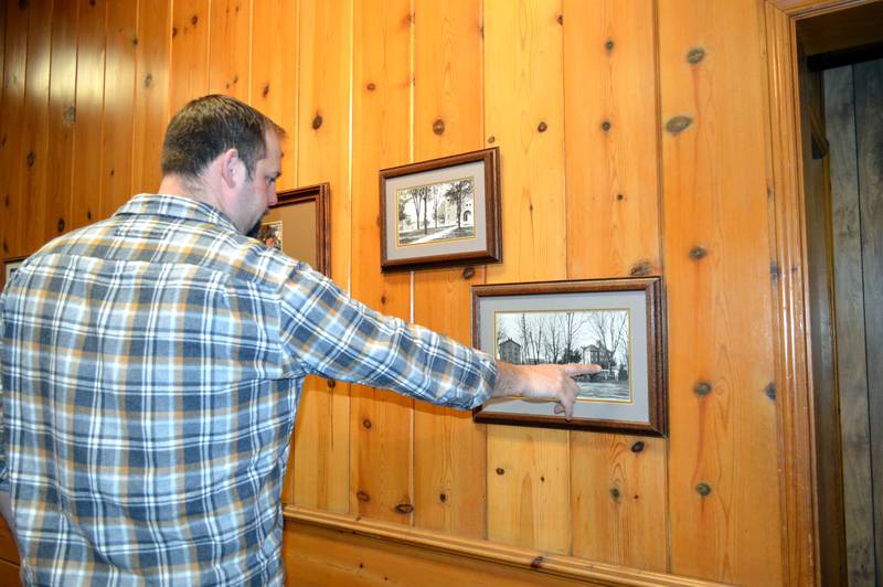John Russell, of rural Mt. Morris, points to an old photo of the Mount Morris College campus hanging on a first floor wall of the former Kable News Company building on April 20, 2023. Russell closed on his purchase of the historic building on March 1; he plans to restore and modify it into multi-use space that benefits the community.