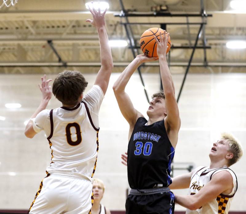 Woodstock's Ty Steponitis shoots the ball between Richmond-Burton's Gavin Radmer (left) and Luke Robinson (right) during a Kishwaukee River Conference boys basketball game on Friay Jan. 9  2026, at Richmond-Burton High School, in Richmond.