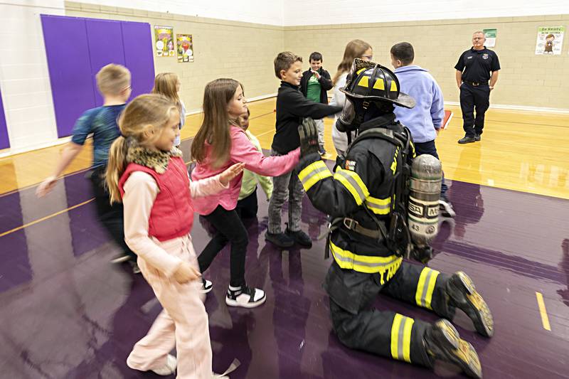 Dixon City firefighter Tyler Hansler gives high fives to third graders at Jefferson School in Dixon Thursday, Oct. 12, 2023 in recognition of Fire Prevention Week. It’s important for kids to recognize and not be scared when seeing a firefighter in all their gear so they can be helped in an emergency.