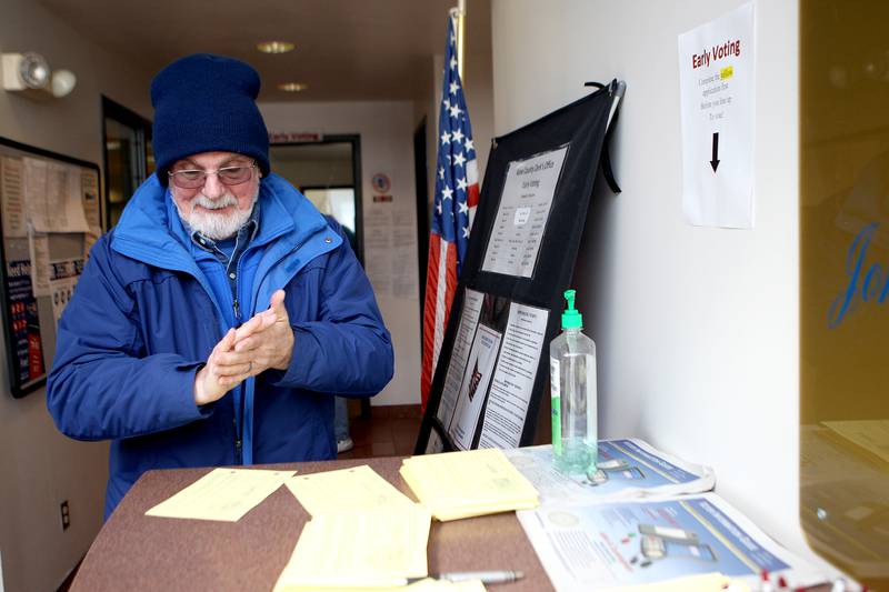 Dennis Trusgnich of Batavia uses hand sanitizer before entering the polling area for early voting at the Kane County Clerk's office in Geneva on March 13. Kane County residents are encouraged to practice social distancing and wash their hands frequently in light of the recent coronavirus outbreak.