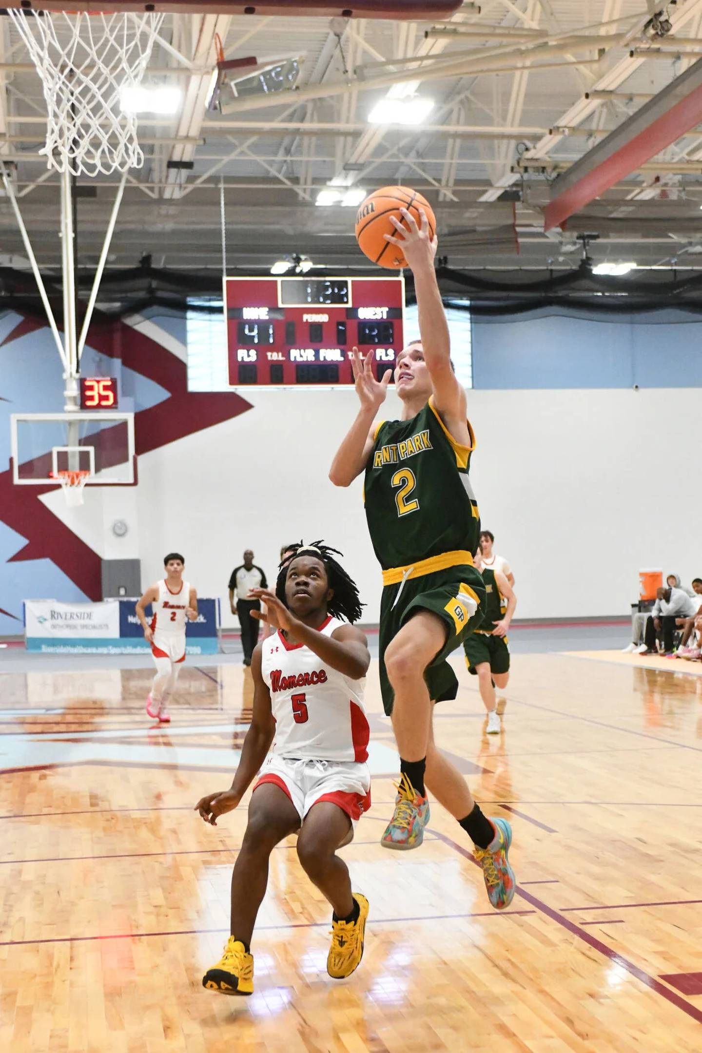Grant Park's Blake Brown breaks away for a layup ahead of Momence's Marchello Draine on Dec. 27, 2024, during Momence's 60-56 victory over the Dragons in consolation bracket play at the Kankakee Holiday Tournament.